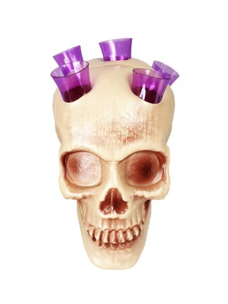 Crânio porta-copos, com cinco copinhos roxos. <a href="https://www.namegafestas.com.br/enfeite-cranio-halloween-porta-copos-com-5-copos-14-cm-roxo.html" target="_blank" rel="noopener">NaMega Festas</a>, R$ 19,90