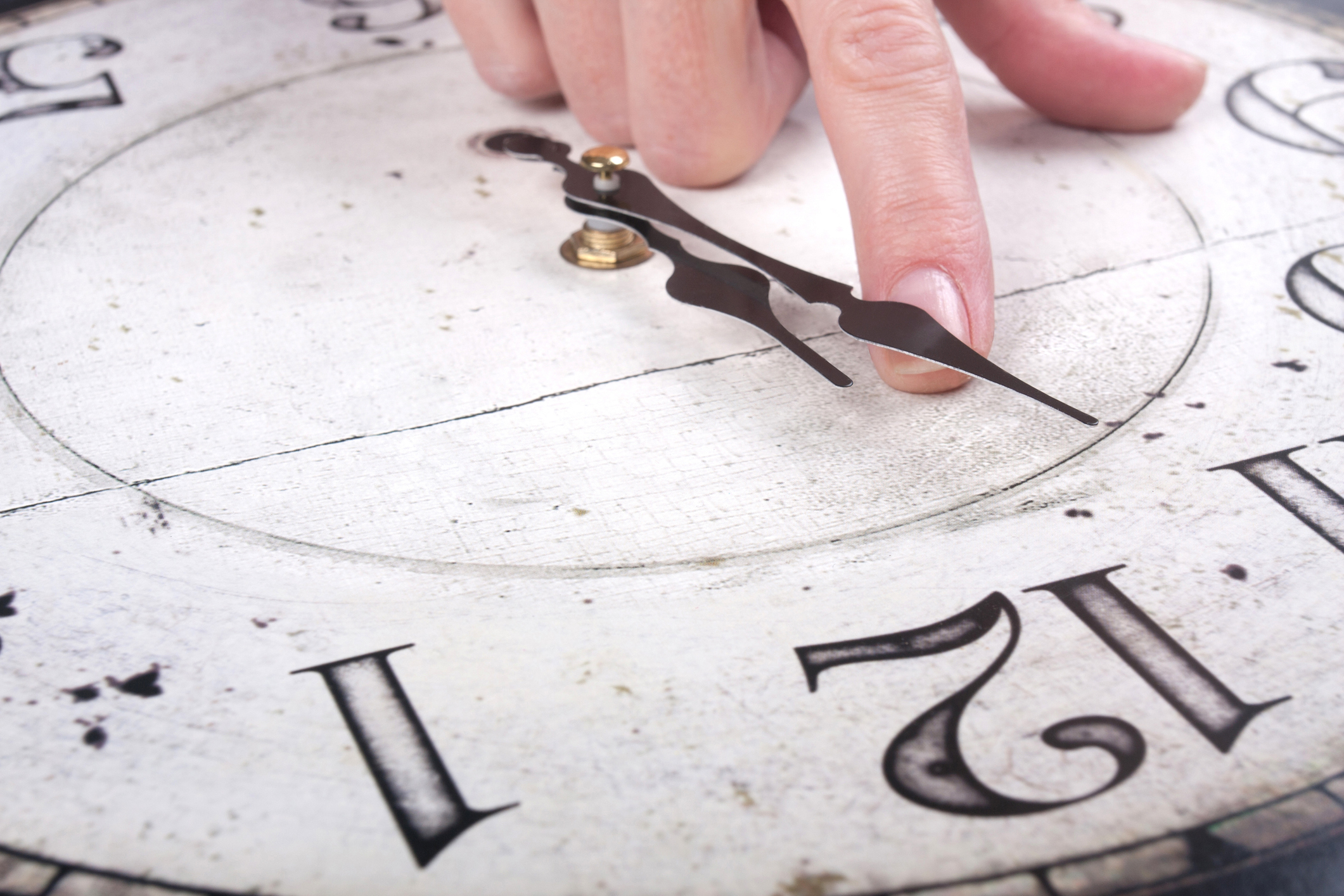 Female finger changes the time on a clock over white