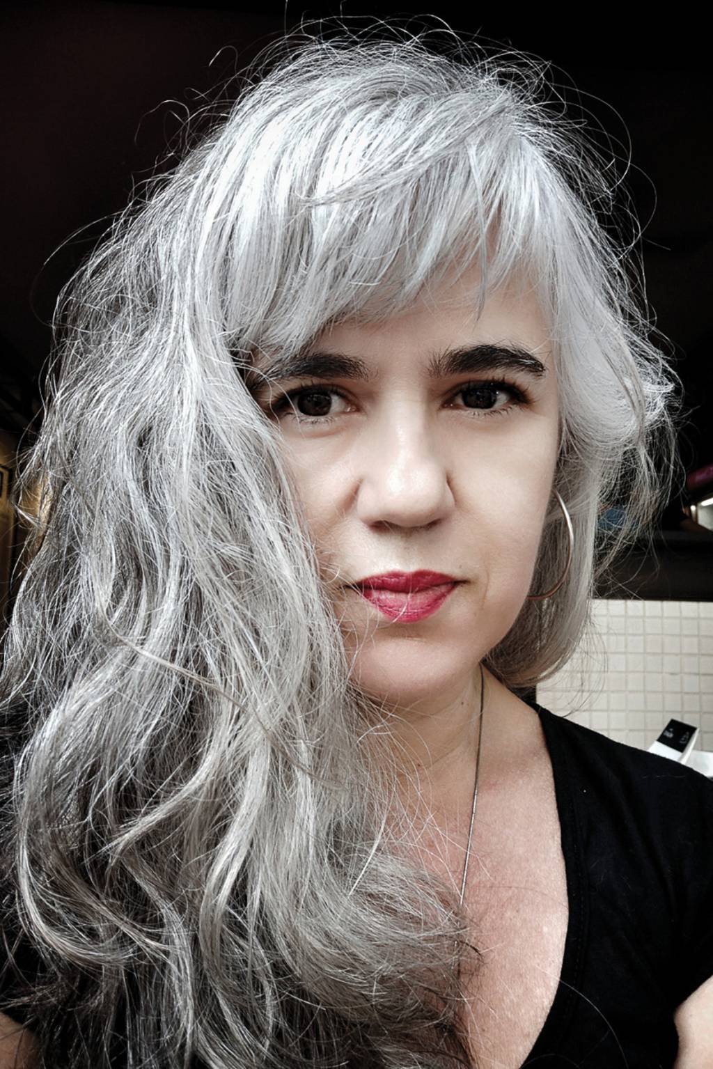 Voluntária Andrea Nestrea Vacina Covid Mulher branca, de cabelos longos e grisalhos, vestindo uma bulsa preta olha para a câmera.