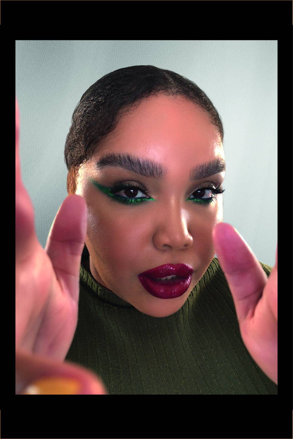 BELEZA2 Mulher com olho delineado verde e batom vermelho olha para a câmera