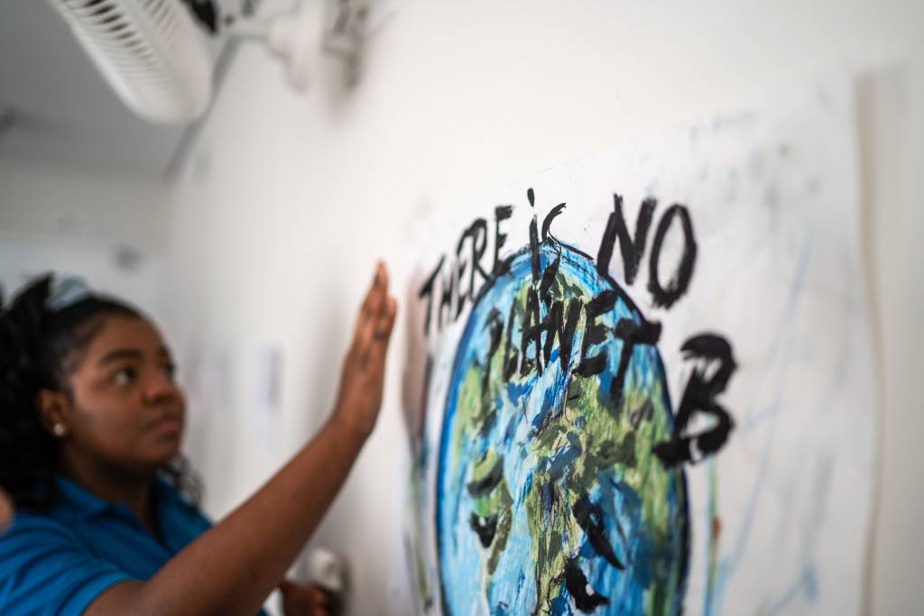 Student fixing in the wall a poster about environmental issues – There is no planet B mudança climática mulheres