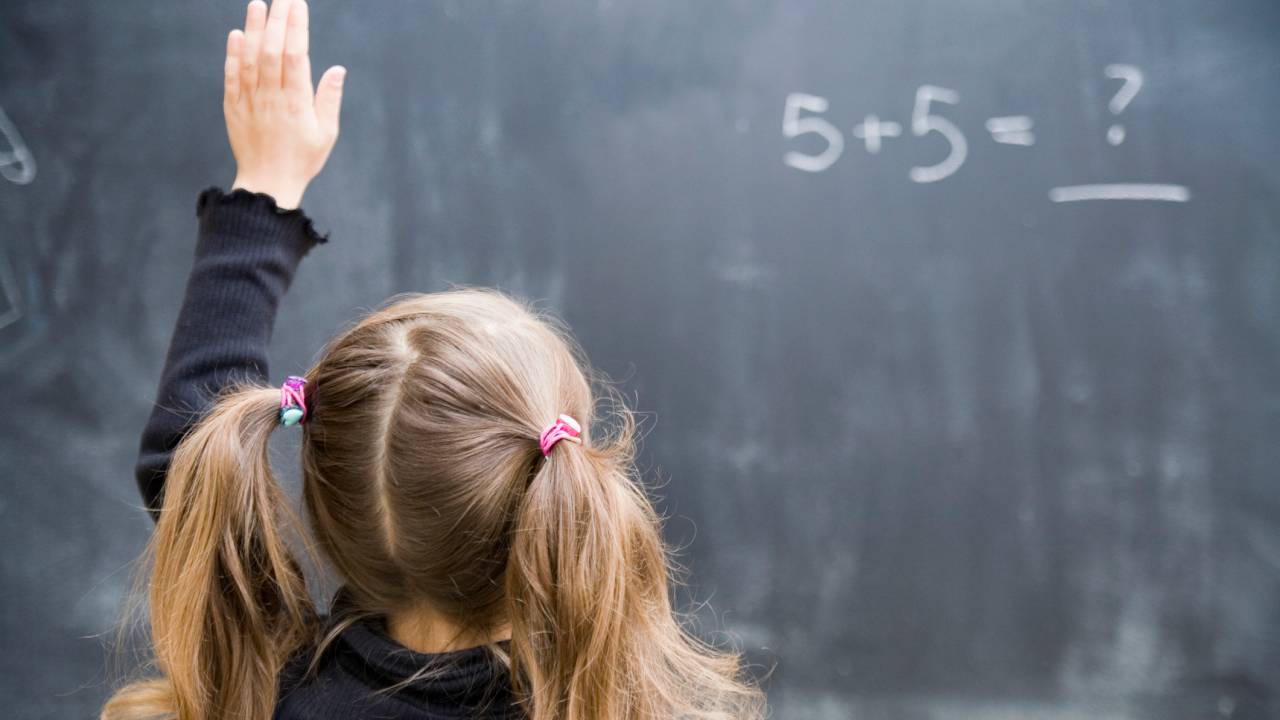 menina com a mão levantada na sala de aula