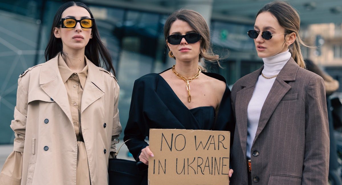 Fashionistas seguram cartaz que pede fim da guerra na Ucrânia durante a semana de moda de Milão.