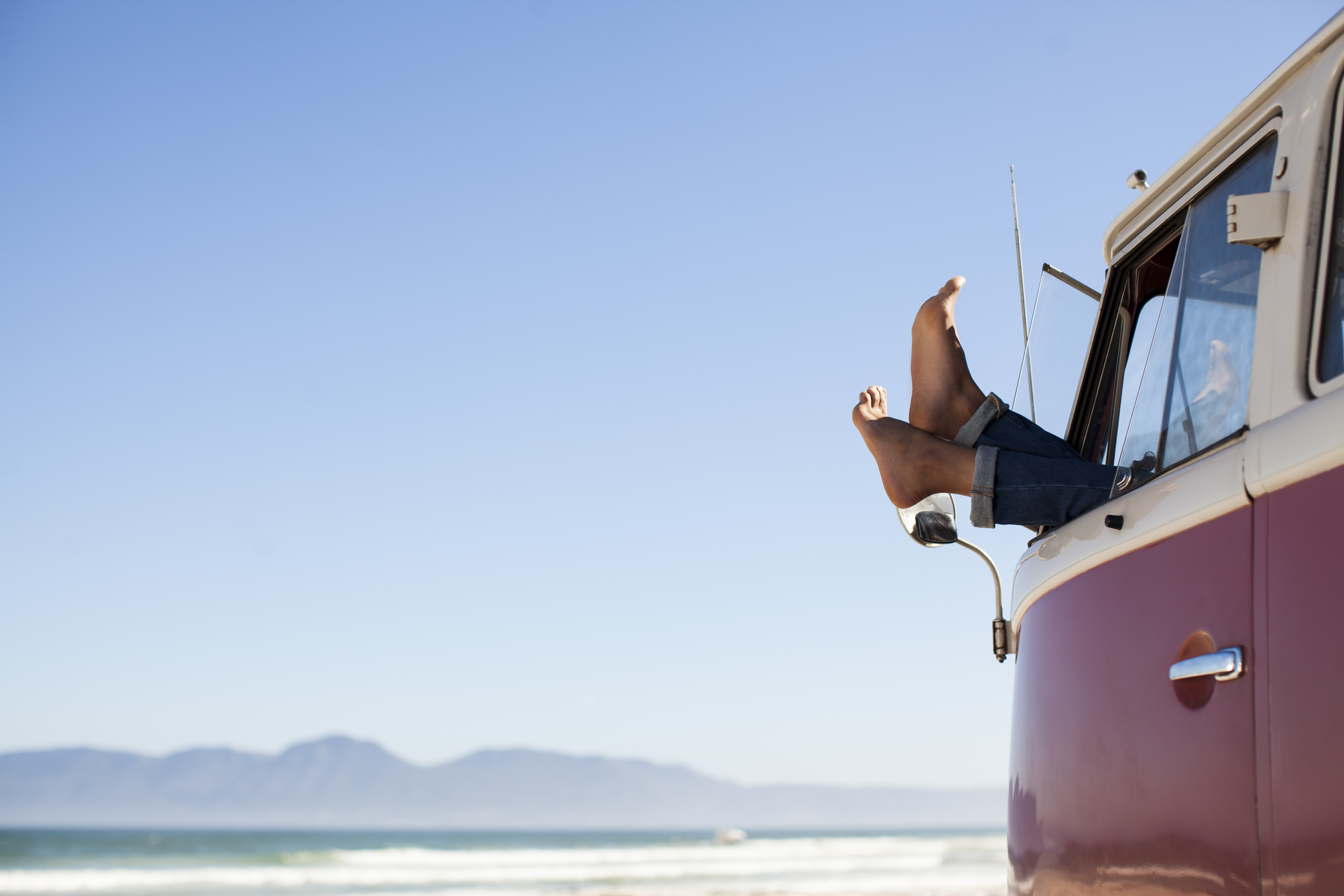 Feet sticking out of camper van window at beach