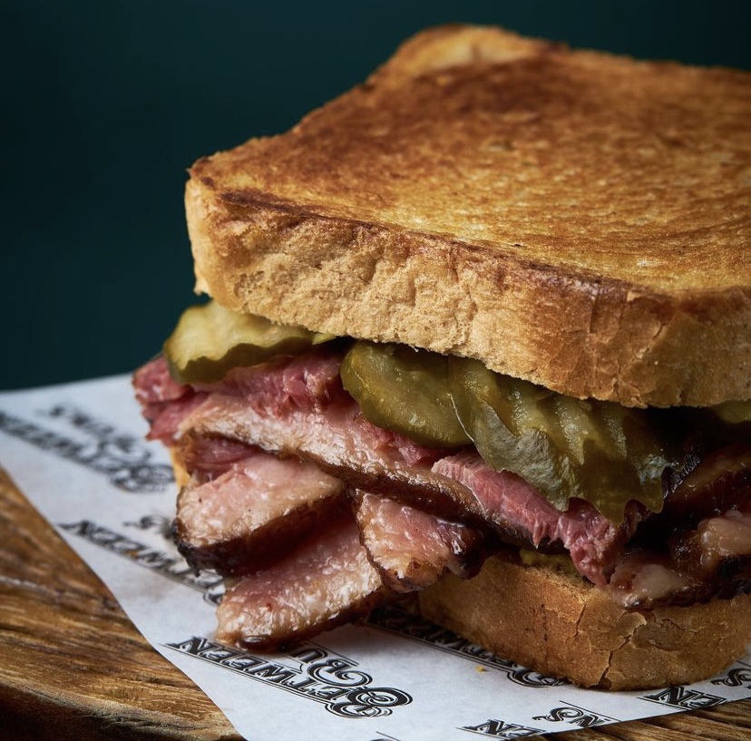 O NY Pastrami, do Between Buns, &eacute; servido no p&atilde;o de centeio e leva pastrami feito na casa, picles de pepino e mostarda de fermenta&ccedil;&atilde;o natural da casa