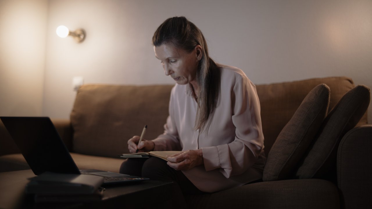 Mulher idosa anotando no computador