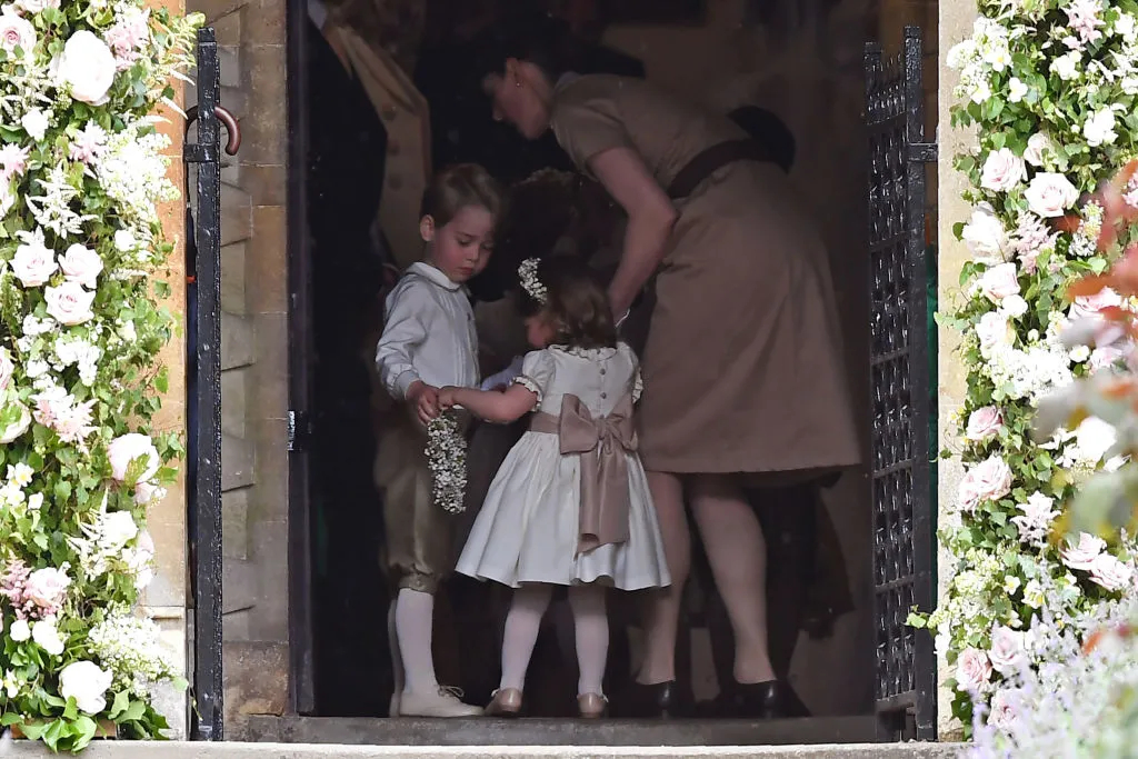 O príncipe George ajuda a irmã Charlotte a carregar a coroa de flores no casamento da tia, Pipa Middleton