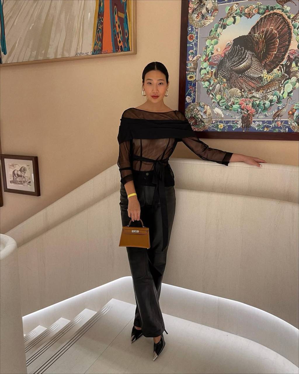 scarpin-calca-jeans Look com calça preta, blusa transparente, bolsa bege e scarpin preto