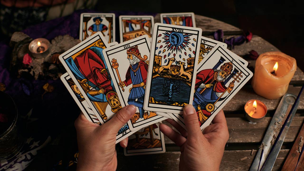 Mãos de vidente lendo cartas de tarô.