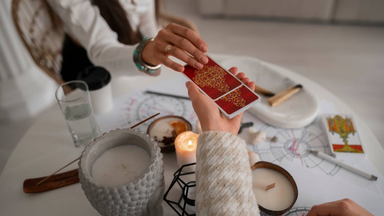 Ângulo alto de uma mulher retirando uma carta de tarô das mãos de uma taróloga.