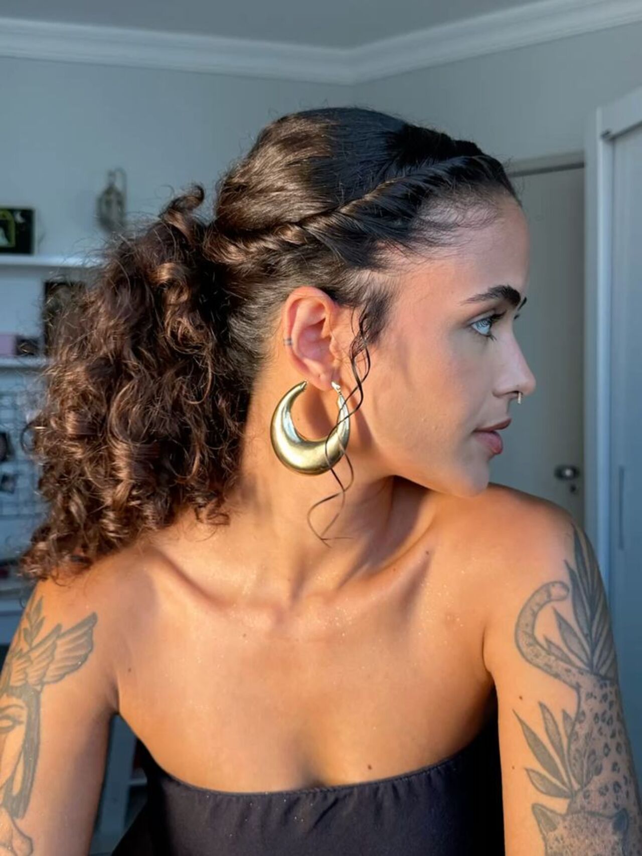 Imagem de mulher morena de perfil com penteado preso com efeito torcido nos fios.