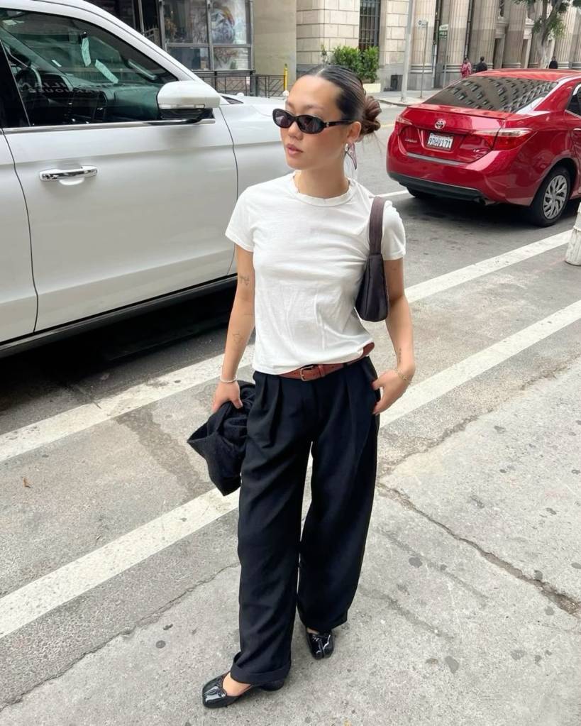 tubi-com-camiseta-branca Pessoa usando camiseta branca e calça de alfaiataria larga preta, combinadas com sapato tabi branco e cinto escuro. Look clean com toque contemporâneo.