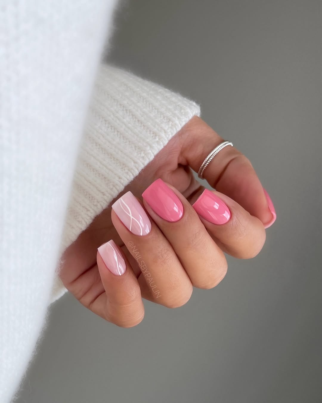 Imagem mostra unhas decoradas delicadas com esmalta&ccedil;&atilde;o rosa e branco, e linhas.