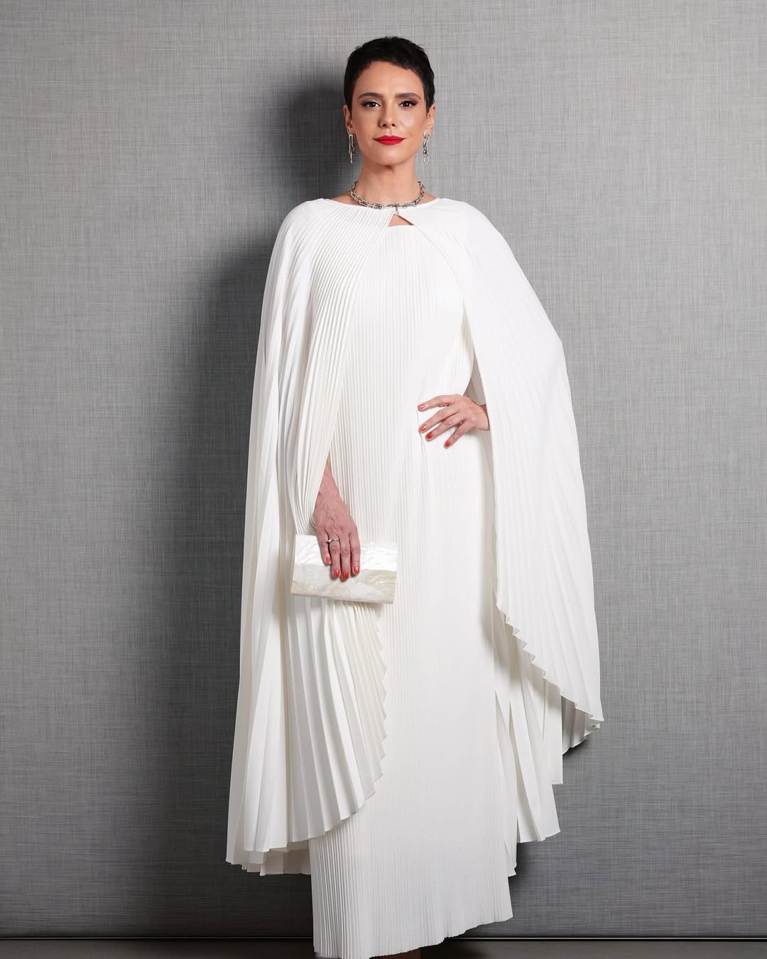 Foto de Malu Galli usando um look composto por vestido branco longo e su&eacute;ter branco