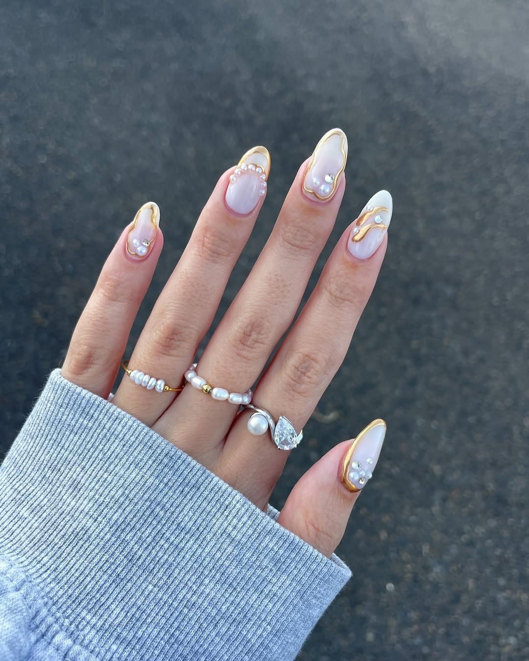 Foto de uma m&atilde;o com as unhas amendoadas coloridas por uma unha delicada e elementos em 3D