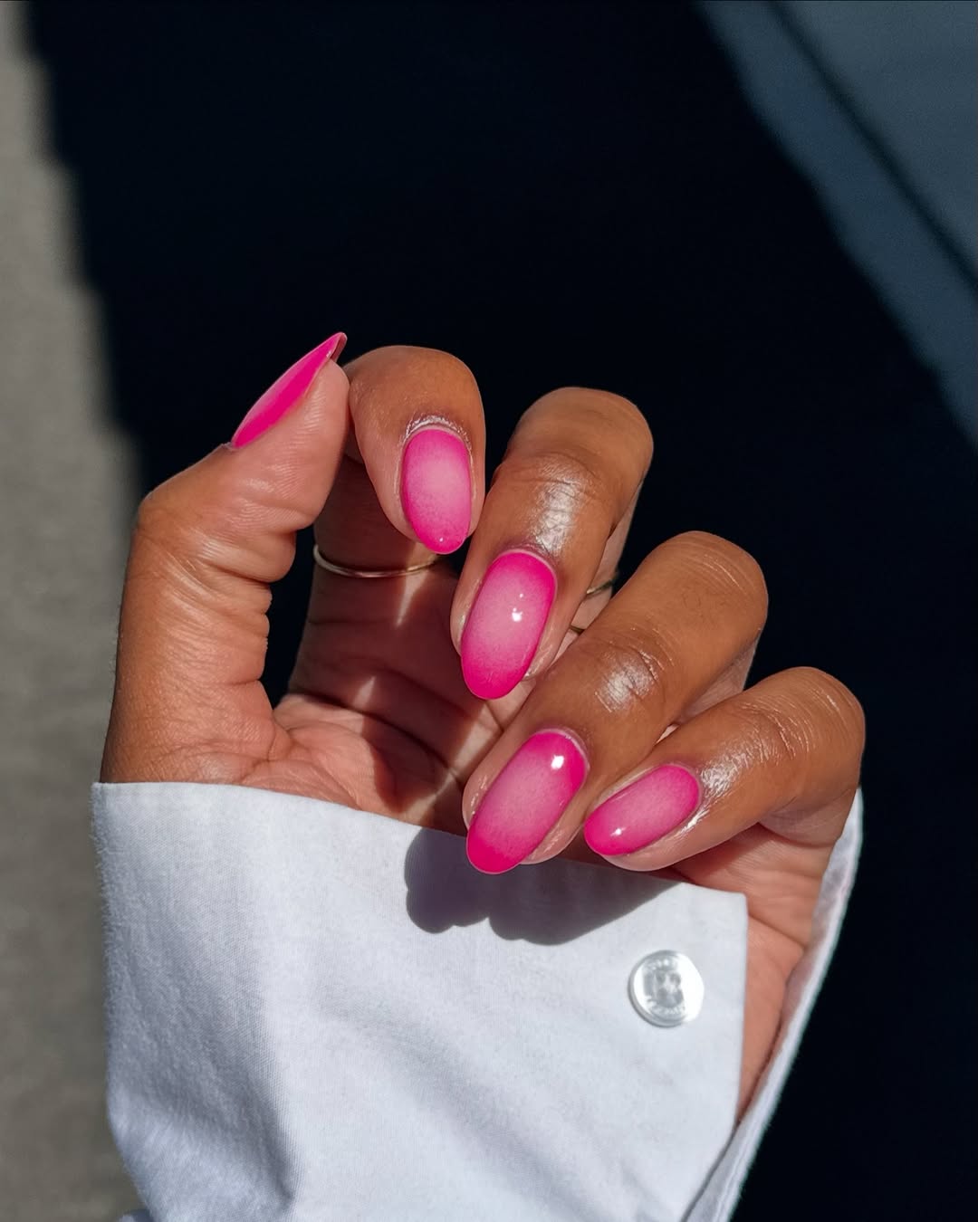 Foto de uma m&atilde;o com as unhas amendoadas coloridas de rosa