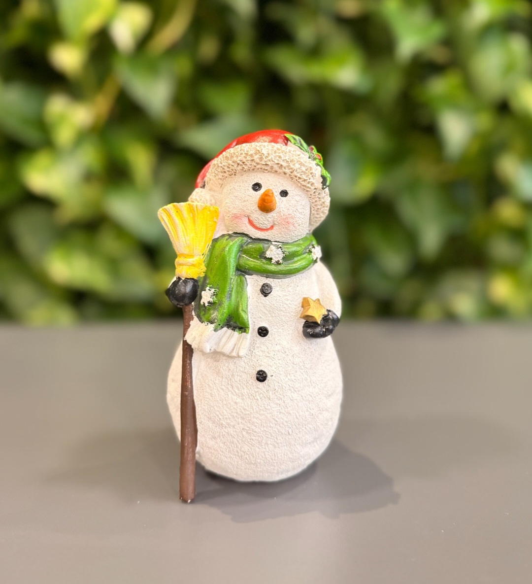 Boneco de neve decorativo com chap&eacute;u, cachecol verde e vassoura amarela, enfeite natalino vendido nos Armarinhos Fernando na Rua 25 de Mar&ccedil;o, em S&atilde;o Paulo. A loja &eacute; conhecida por op&ccedil;&otilde;es baratas de decora&ccedil;&atilde;o de Natal, como estrelas douradas e figuras tem&aacute;ticas