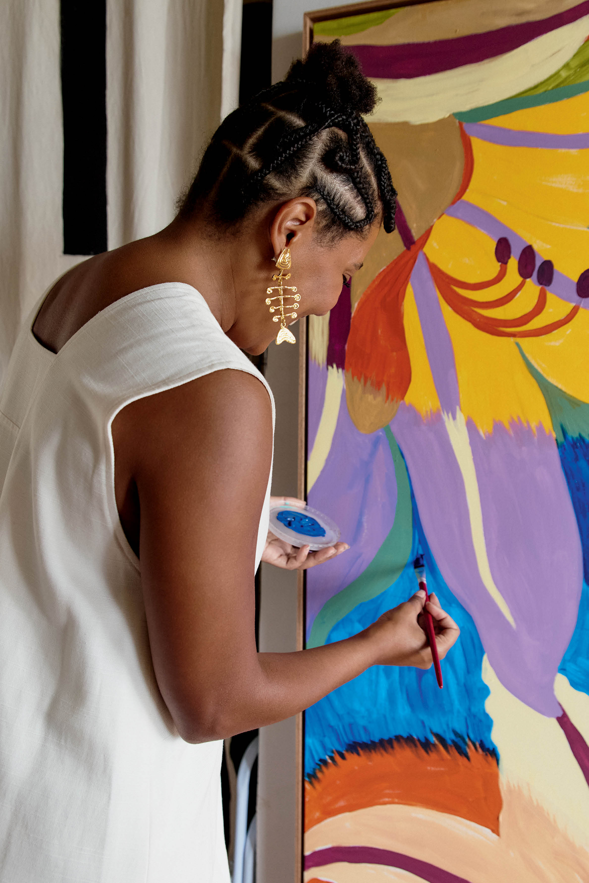 Mulher de costas pintando parede colorida.