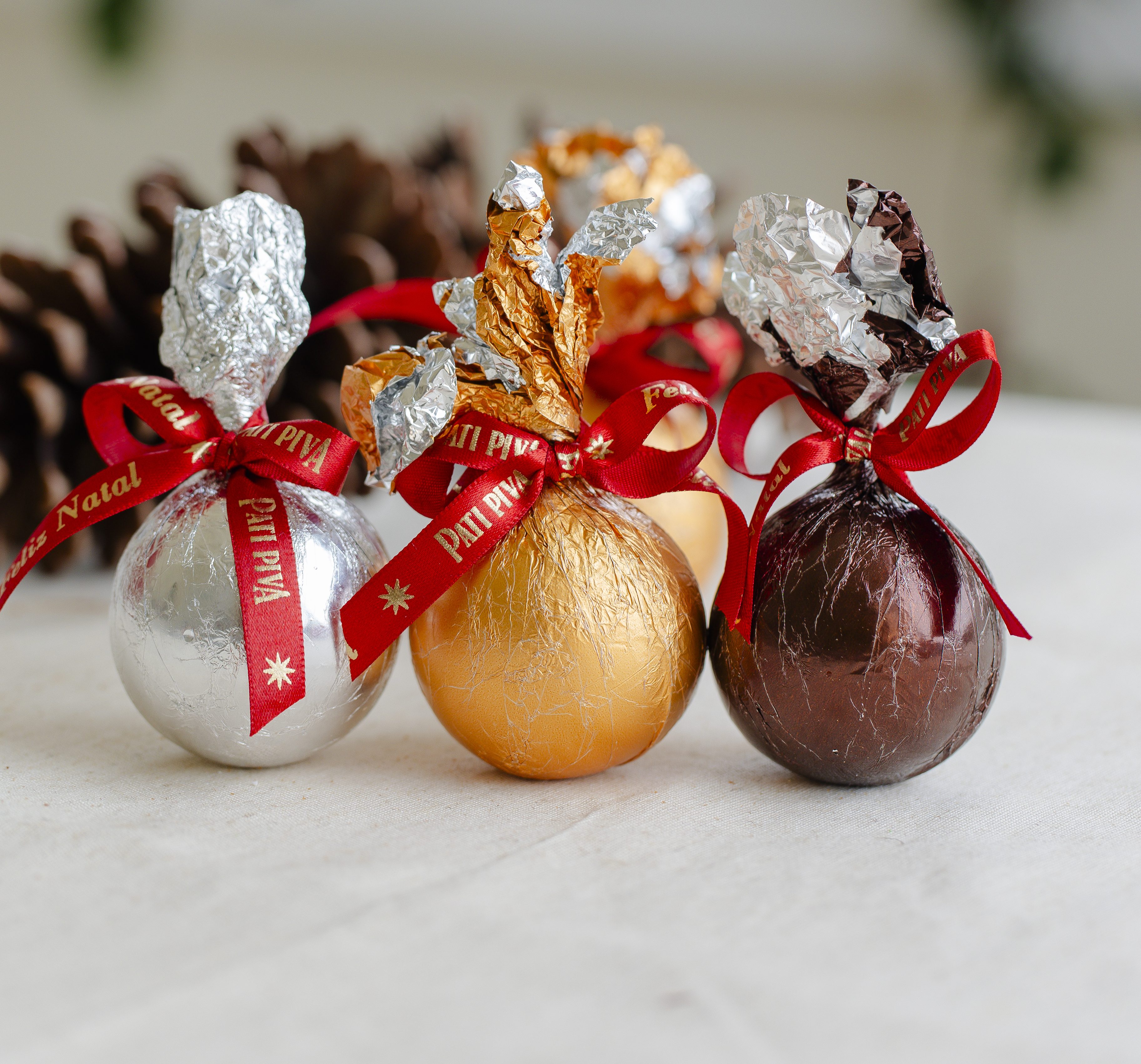olas de Natal comest&iacute;veis da Pati Piva, embaladas em papel metalizado dourado, prateado e marrom, com la&ccedil;os vermelhos. Foto destaca os tradicionais enfeites de chocolate da confeitaria Pati Piva, em S&atilde;o Paulo, conhecidos por decorar e ado&ccedil;ar a ceia de fim de ano