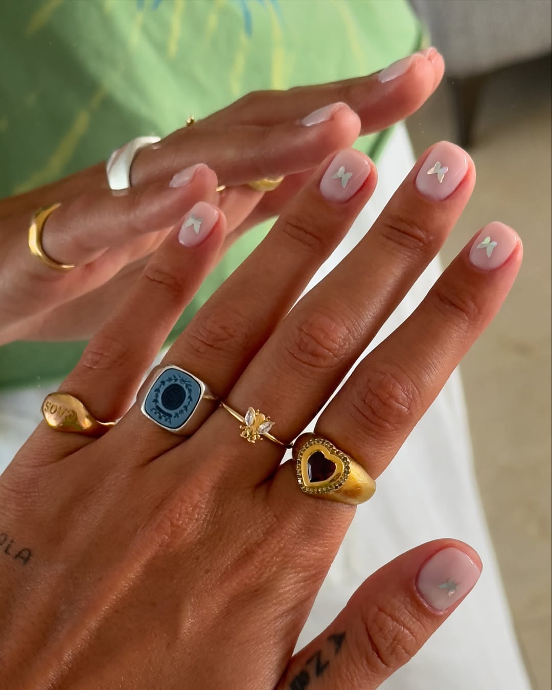 Foto de uma m&atilde;o com as unhas transparentes e com aplica&ccedil;&otilde;es de borboletas