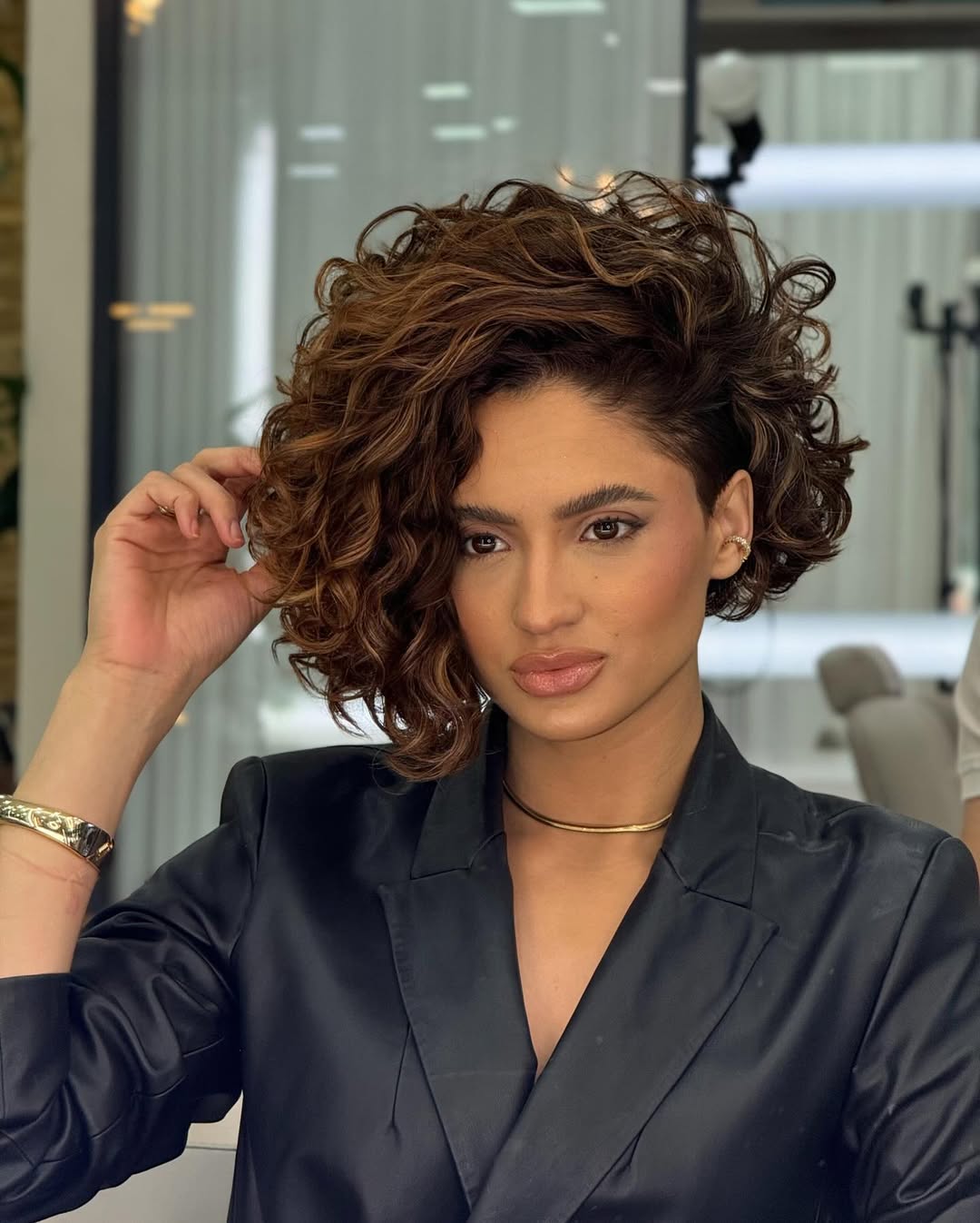 Mulher morena com cabelo chanel cacheado jogado de lado