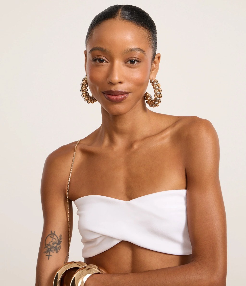 Foto de uma mulher negra usando um look composto por top branco