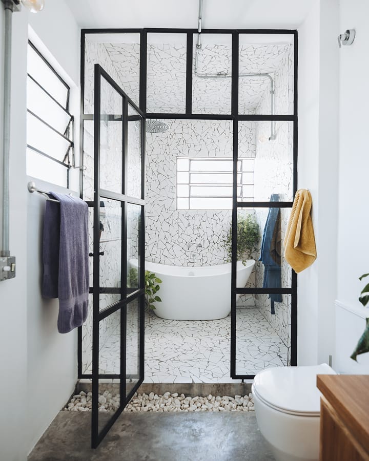 banheiro com piso e paredes de caquinho branco e banheira ao fundo