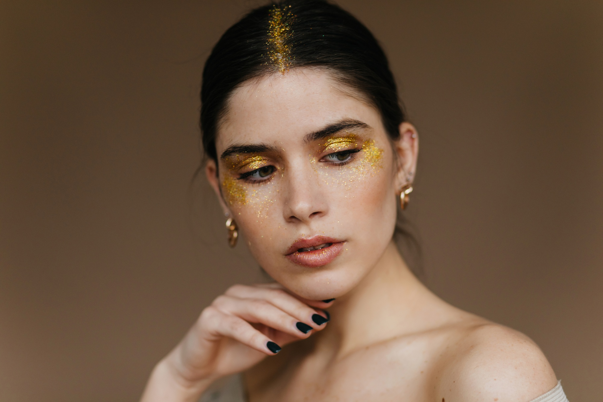 Close em maquiagem com glitter dourado aplicado nas p&aacute;lpebras e bochechas, inspira&ccedil;&atilde;o de make carnavalesca e imagem ilustrativa para mat&eacute;ria sobre como tirar glitter do rosto sem irritar a pele.