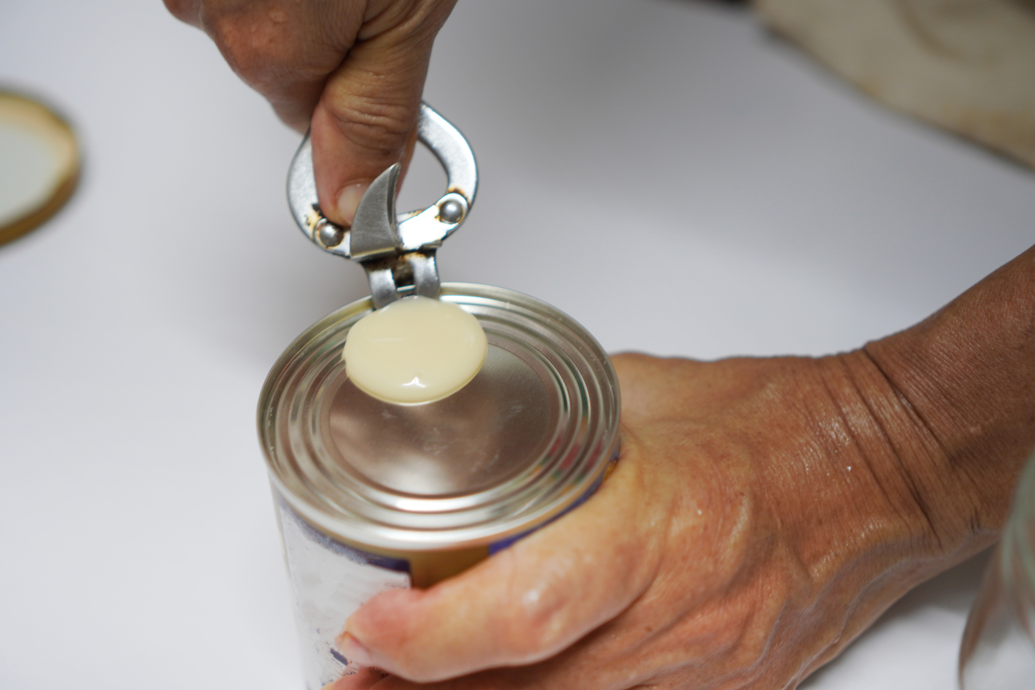 Imagem mostra uma lata de leite condensado sendo aberta, em referência à interdição determinada pela Anvisa após testes apontarem contaminação bacteriana acima do permitido.