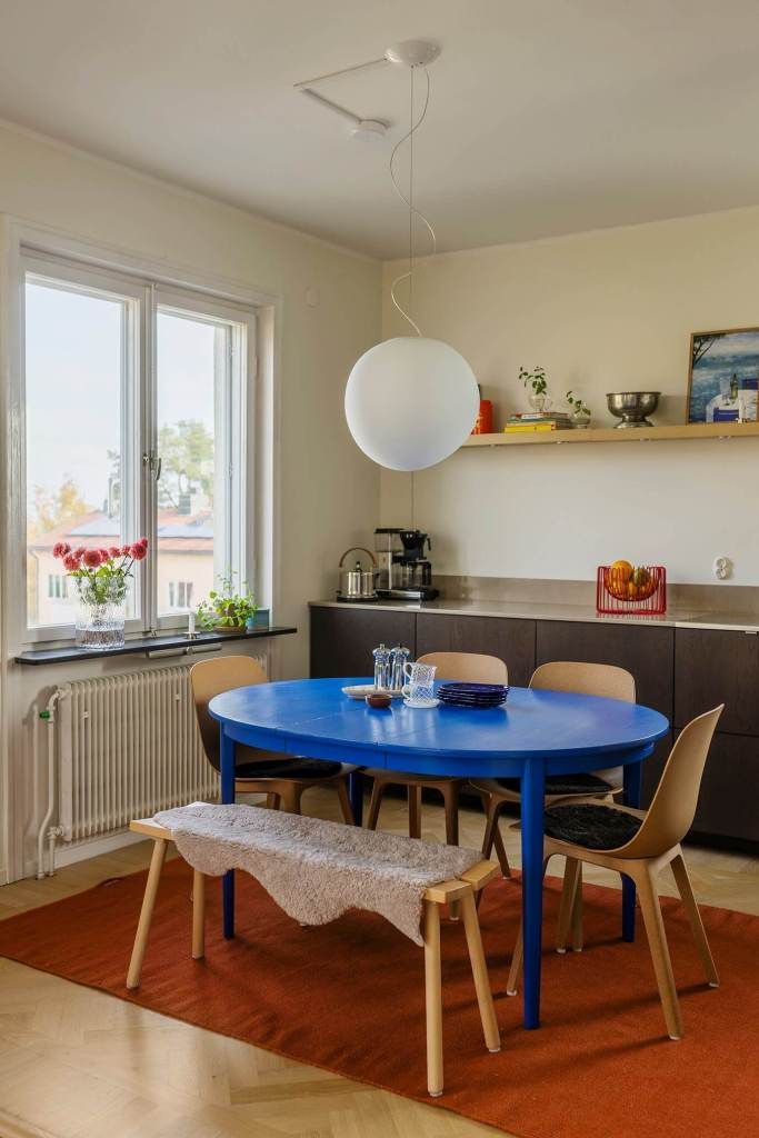 Sala de jantar com mesaa oval azul e tapete vermelho