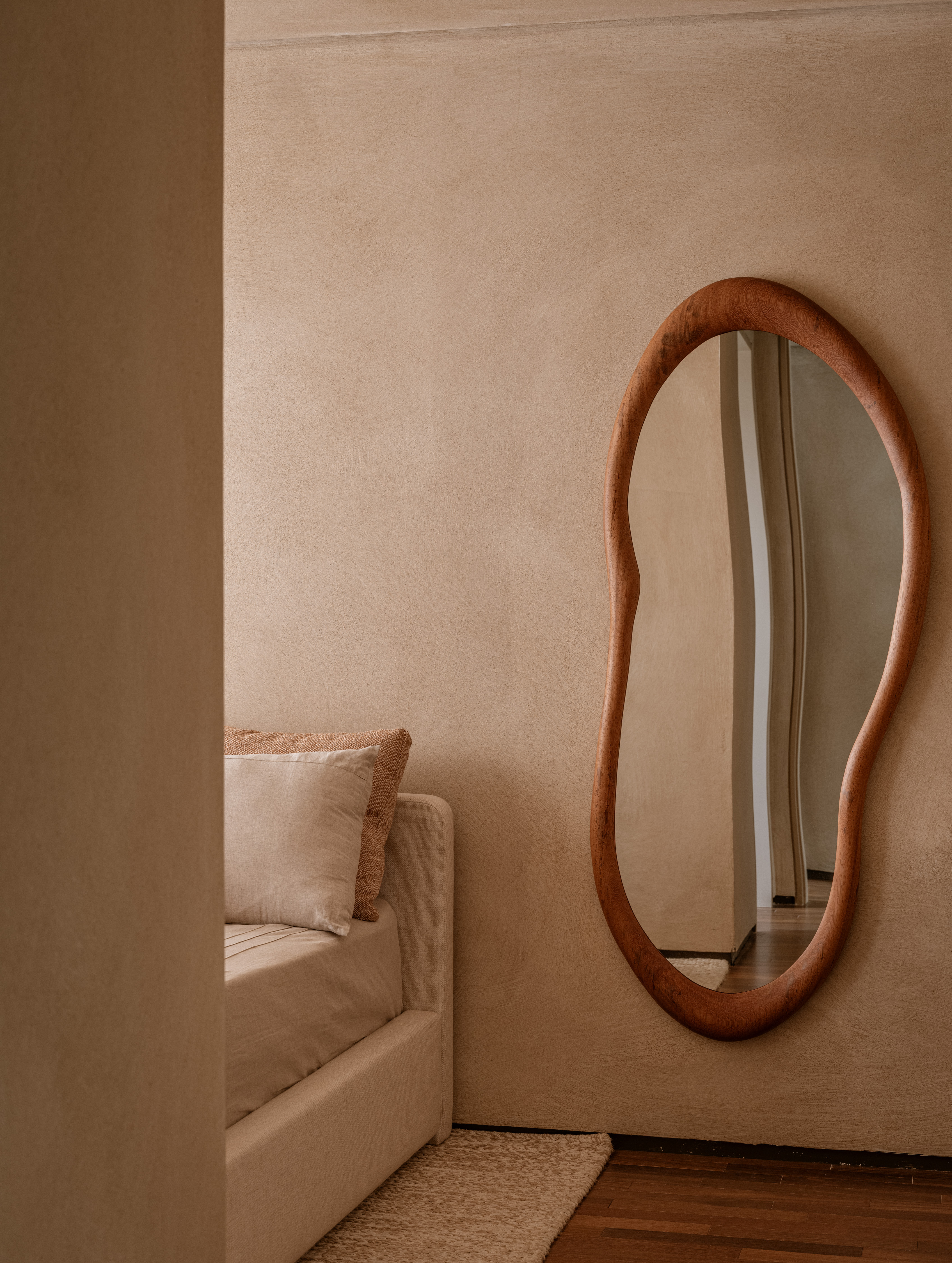 Quarto minimalista com espelho em formato org&acirc;nico marrom