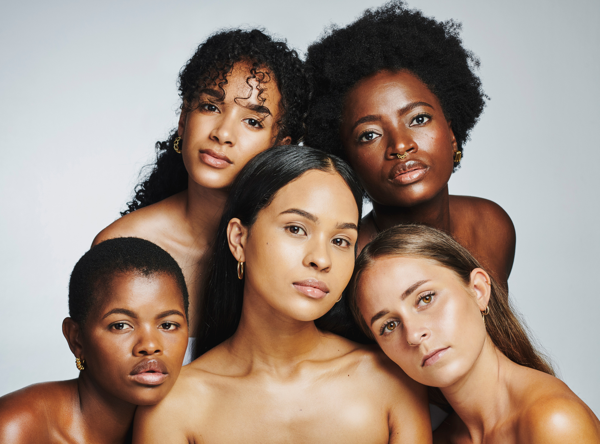 Beauty portrait of a diverse group of beautiful women posing together against a grey studio background. Faces of female models with perfect, clear skin and complexion from a daily skincare routine