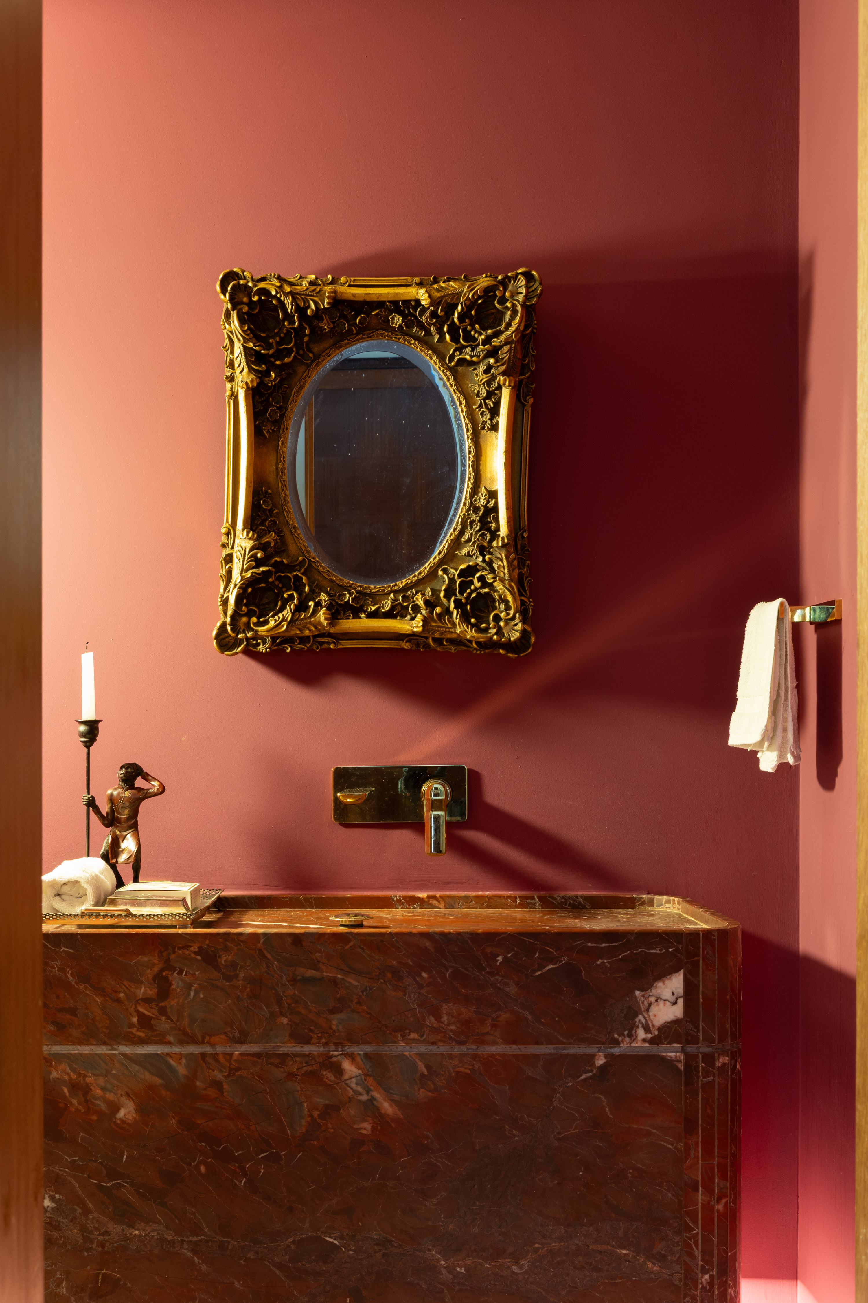 Lavabo com paredes vermelhas e espelho cl&aacute;ssico dourado