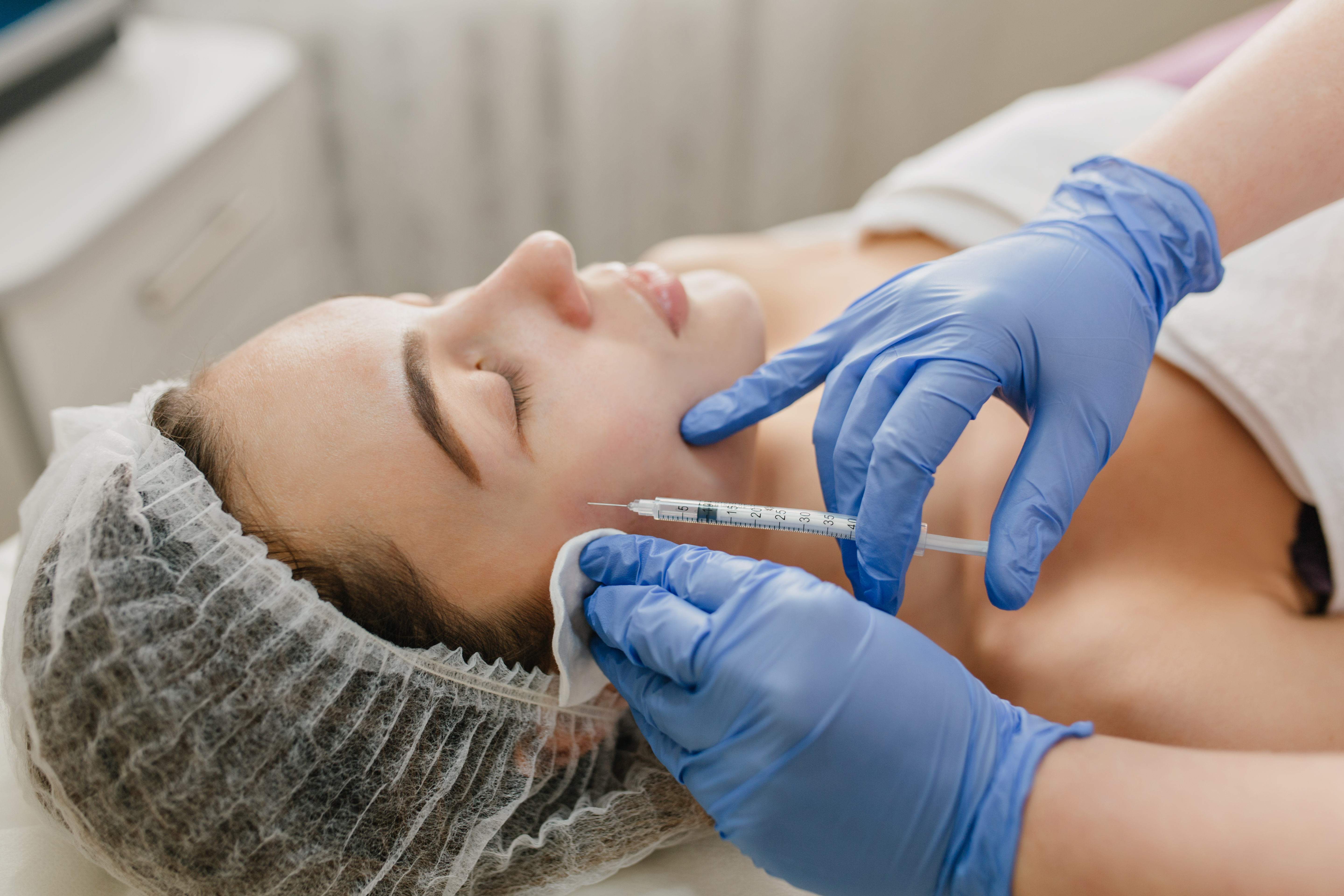 Foto de uma mulher jovem, morena, recebendo a aplica&ccedil;&atilde;o de botox no rosto