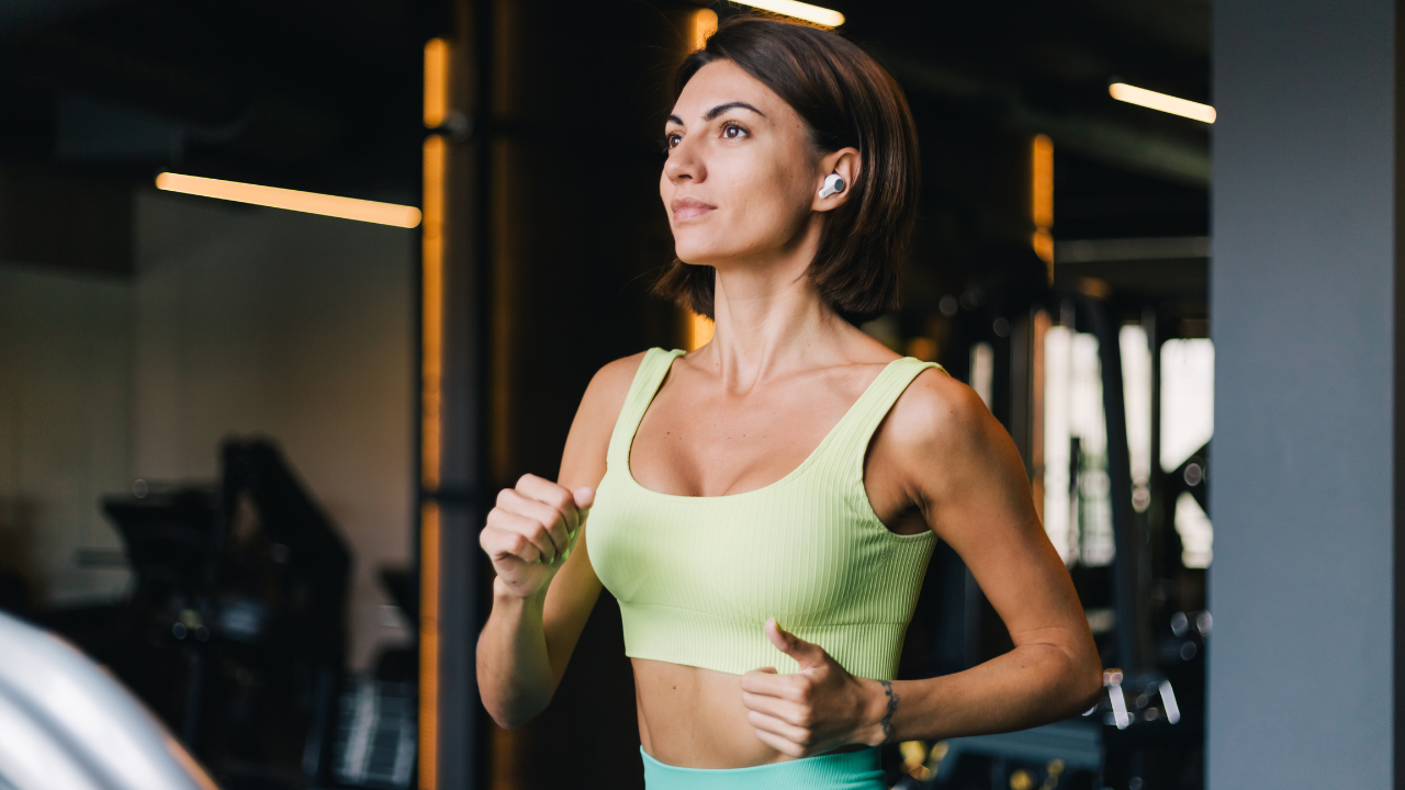 Mulher de look de academia verde limão correndo na esteira