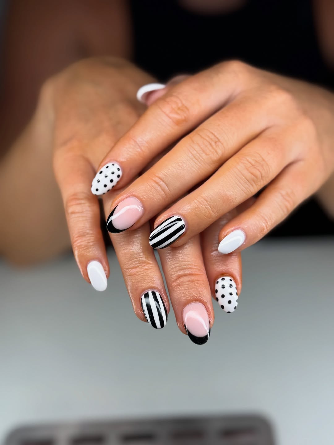 Unhas brancas decoradas com listras, po&aacute;s e desenhos gr&aacute;ficos em preto