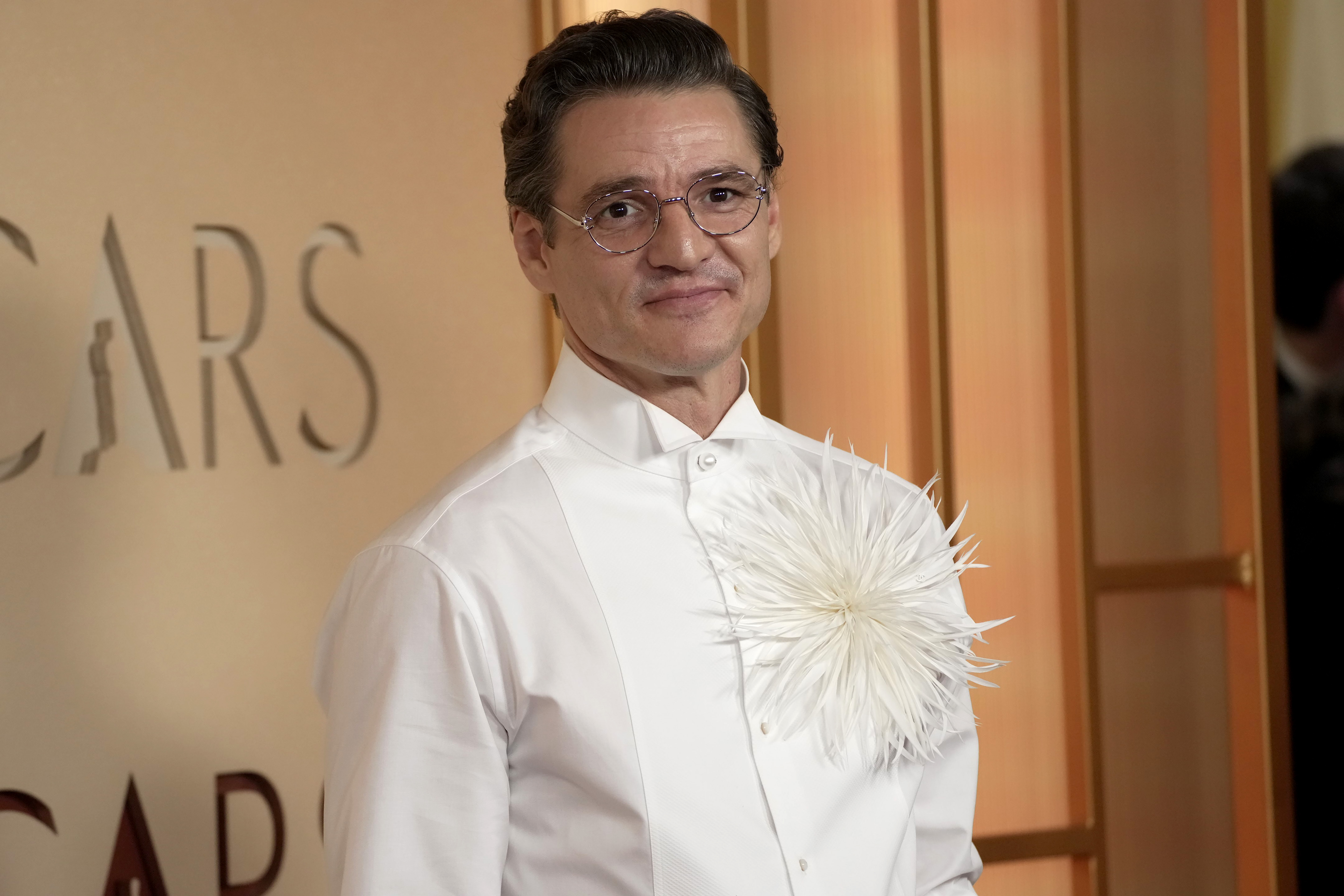 edro Pascal posa no tapete vermelho do Oscar 2026 sem bigode, usando camisa branca com detalhe floral
