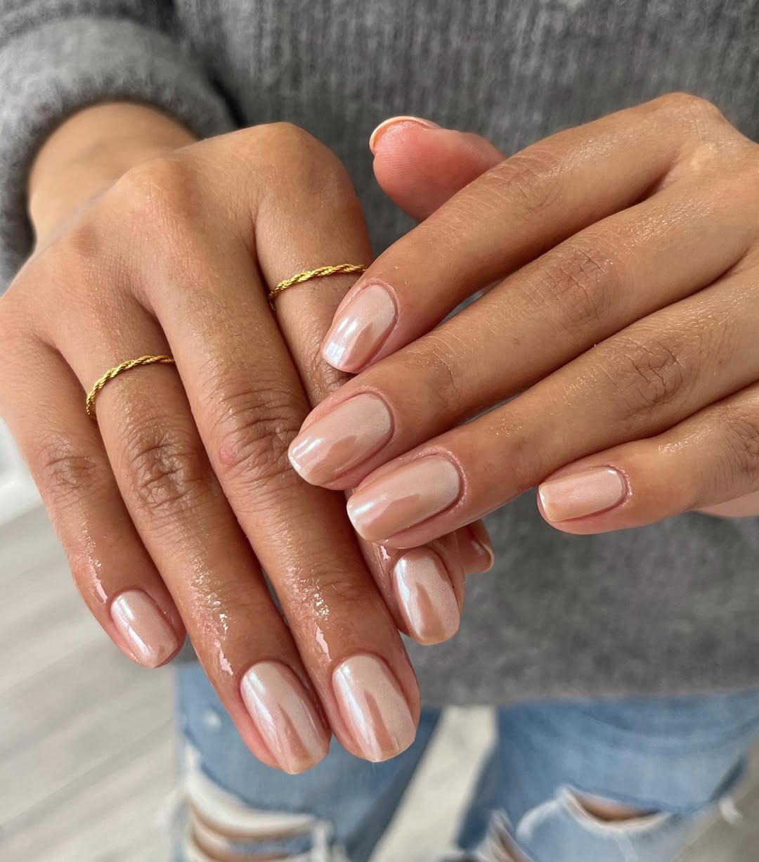 Foto de uma m&atilde;o com unhas coloridas de nude e brilhantes