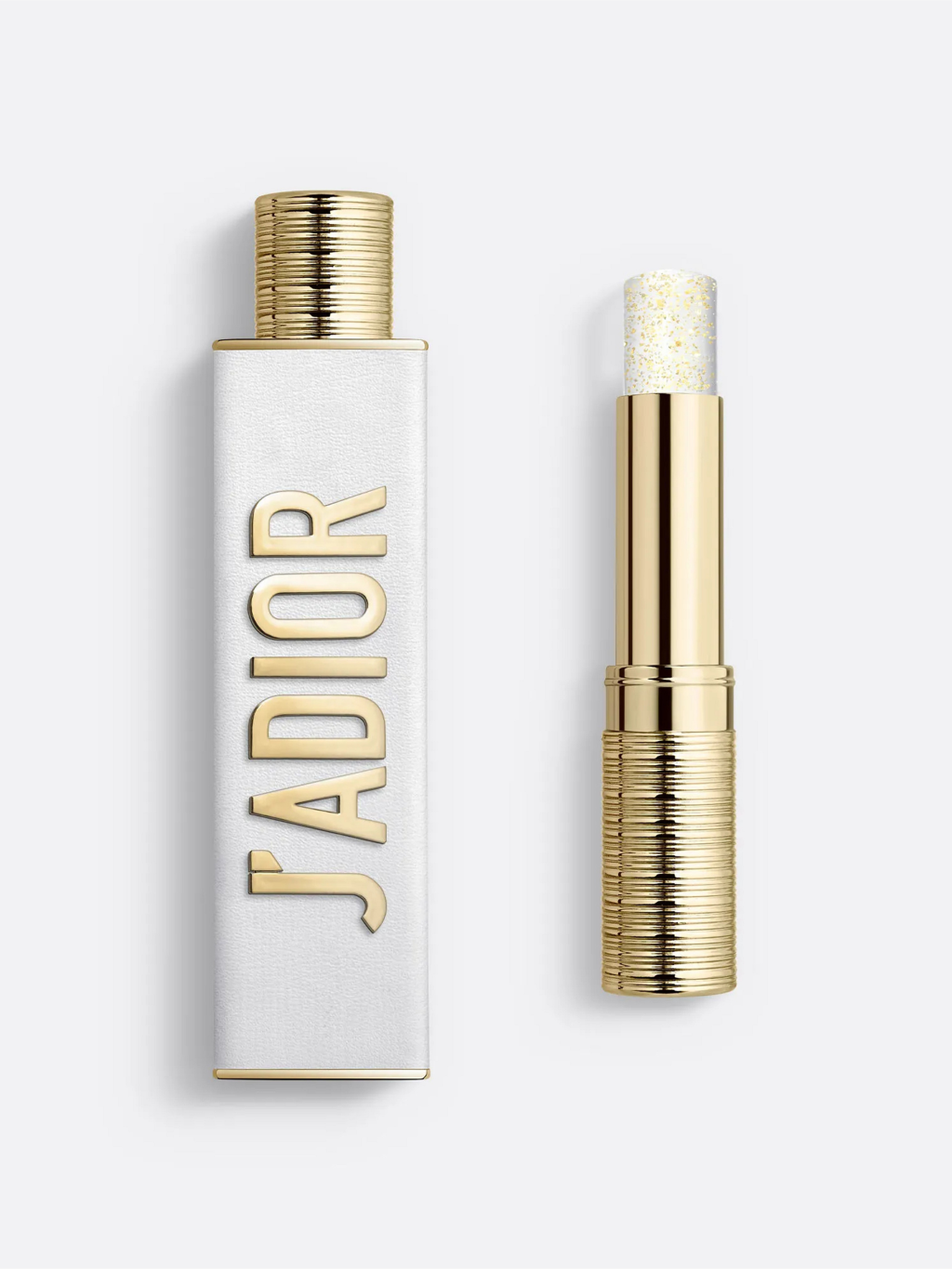 Frasco retangular branco com tampa dourada e o nome JADIOR em letras douradas verticais, ao lado de um batom dourado com brilho dourado na ponta, sobre fundo branco