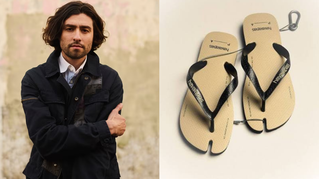 Homem de cabelo e barba escura, vestindo jaqueta preta e camisa branca, braços cruzados, olhando para frente. Ao lado, um par de chinelos Havaianas bege com tiras pretas, com um design que separa o dedão dos outros dedos, presos por um gancho metálico