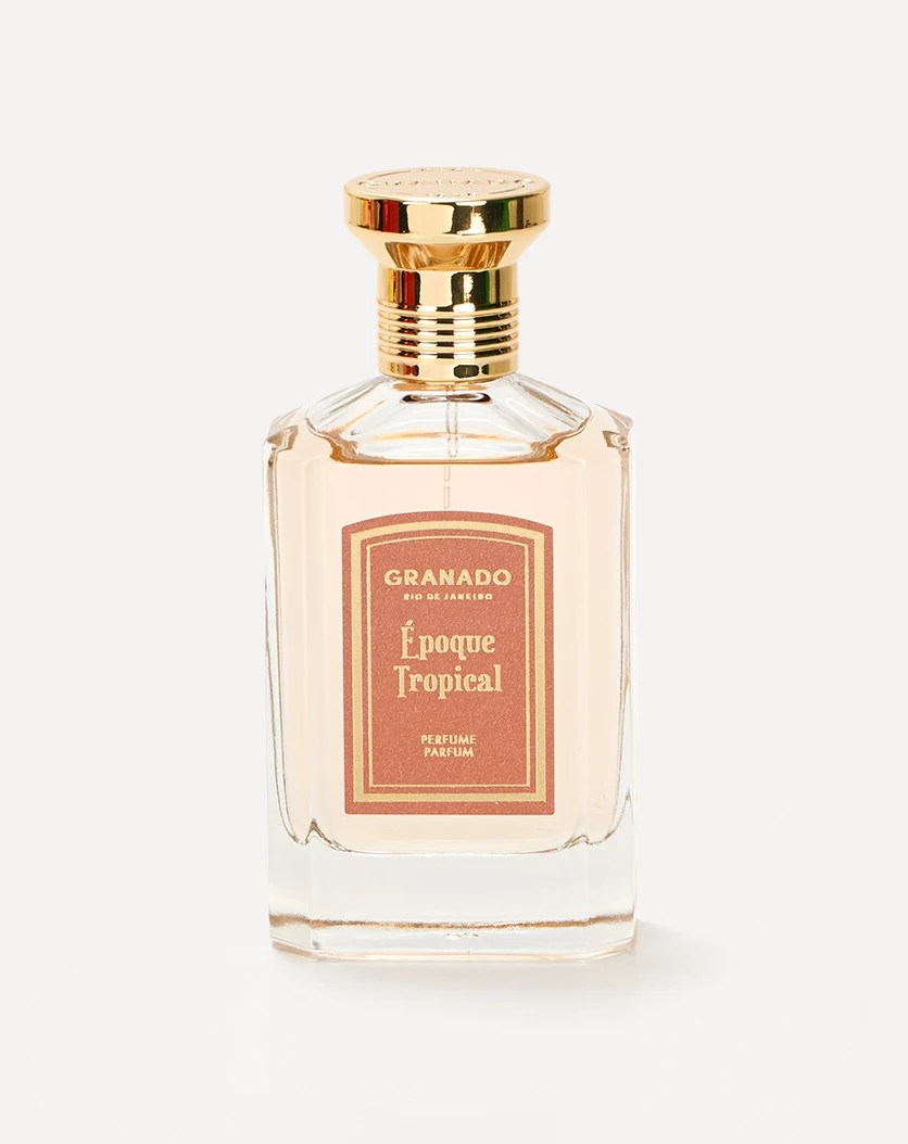 Frasco de perfume Granado &Eacute;poque Tropical, com l&iacute;quido bege claro, tampa dourada e r&oacute;tulo retangular marrom-rosado com borda dourada, sobre fundo branco