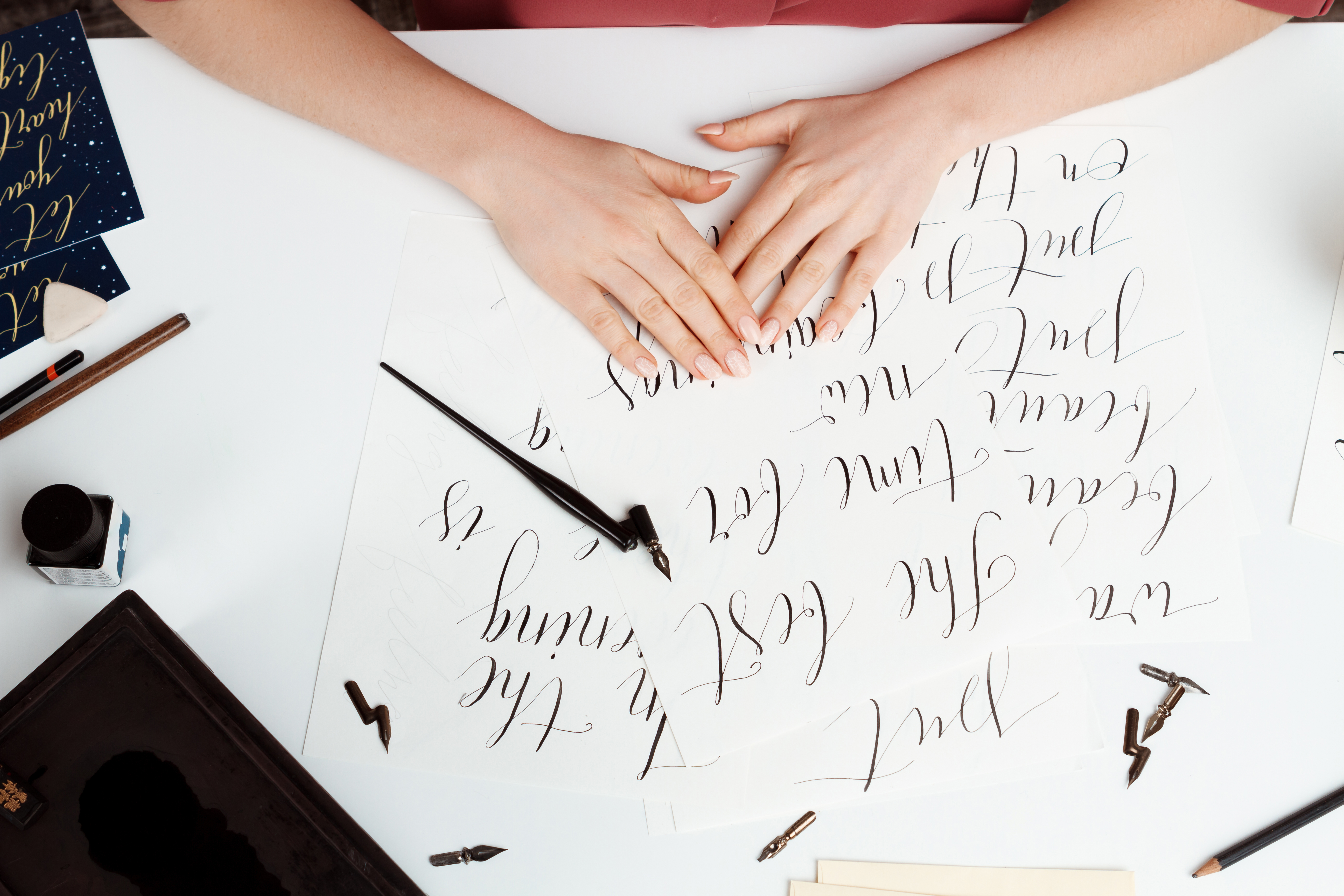 Girl writing calligraphy on postcards. Art design. Above.