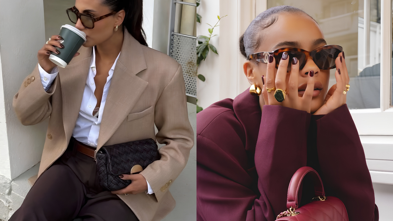 Duas mulheres com óculos escuros e unhas escuras. À esquerda, uma mulher de blazer bege e calça marrom bebe café, segurando uma bolsa preta. À direita, uma mulher de blazer vinho e anéis dourados, com as mãos no rosto, segura uma bolsa vermelha